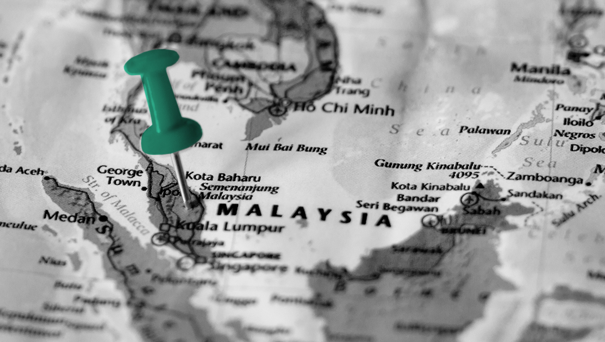 Photo of a map with Southeast Asia in focus, with a green thumbtack centered on Malaysia