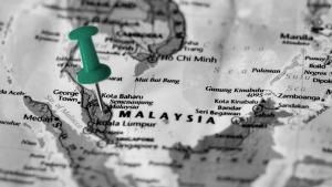 Photo of a map with Southeast Asia in focus, with a green thumbtack centered on Malaysia